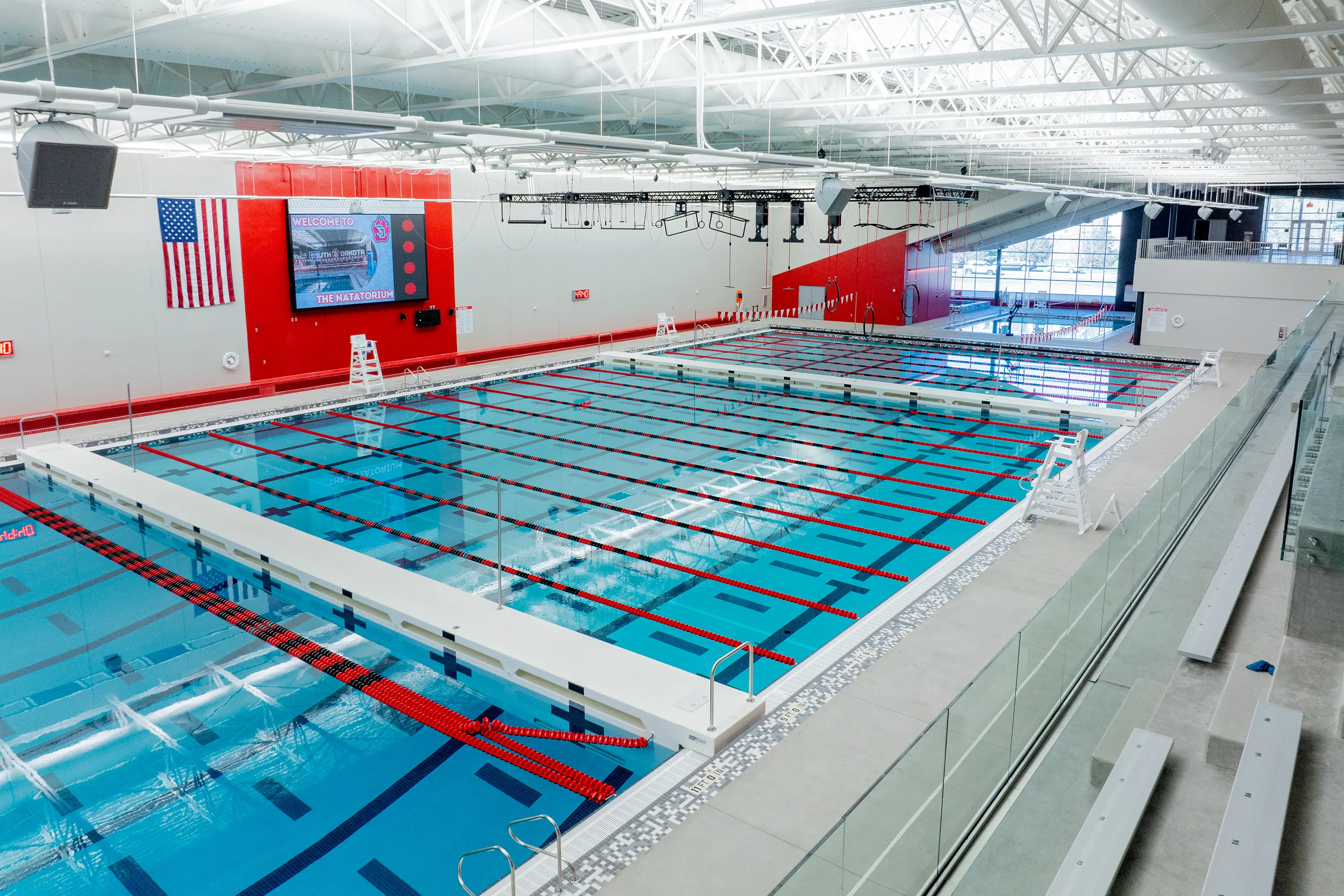Usd Natatorium Wellness Center 26 Spectator view down the pool lanes from mezzanine seating with precast stadia visible.