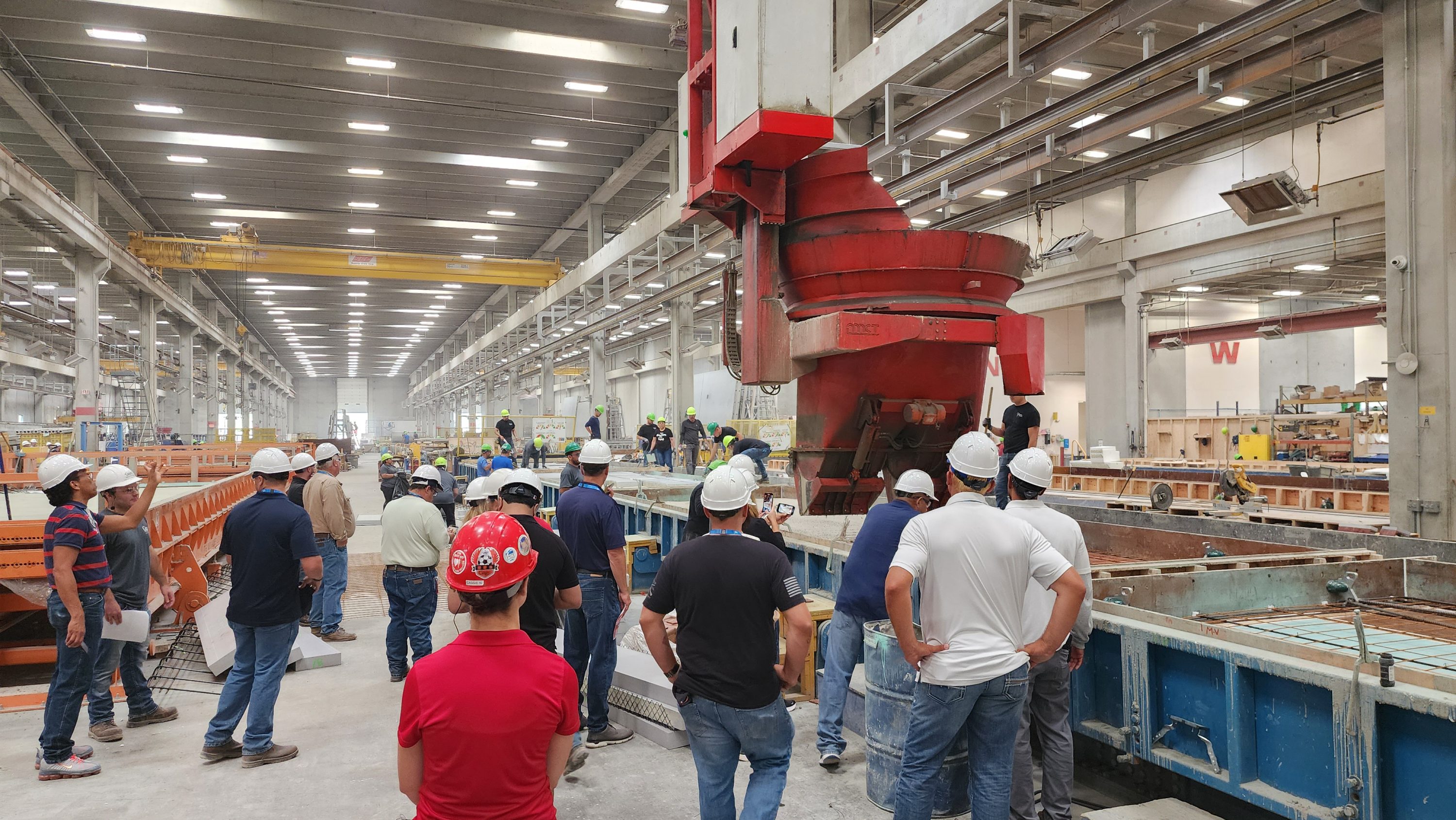 Precast manufacturing plant pouring concrete architectural panels for tour attendees.