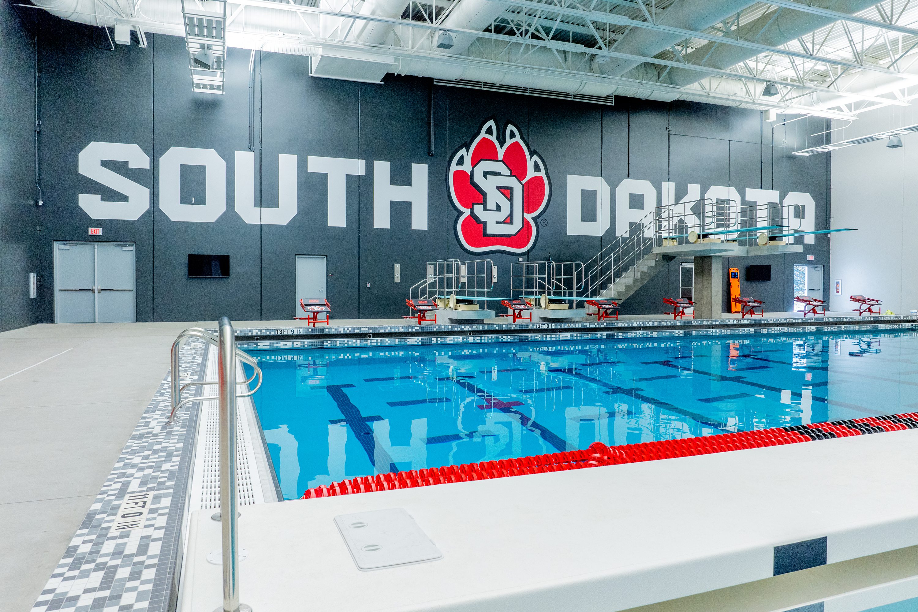 Mid-pool view with South Dakota logo and diving boards above competition lanes.